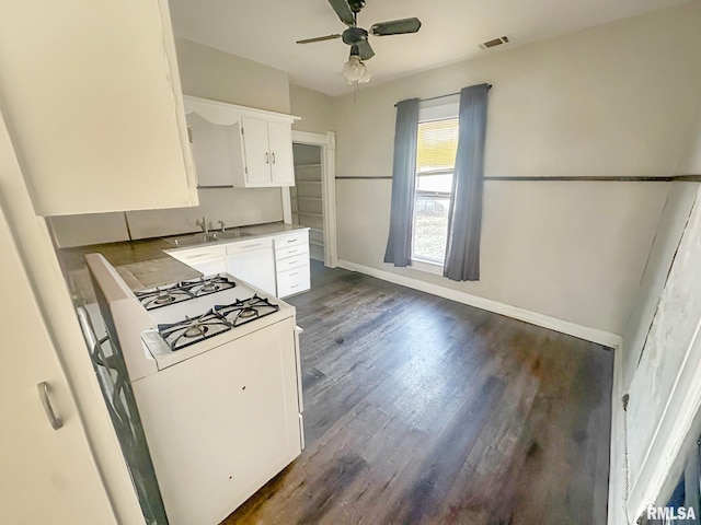 kitchen featuring baseboards, dark wood-style flooring, gas range gas stove, white cabinetry, and a sink