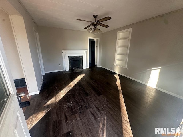 unfurnished living room with ceiling fan, built in features, and dark hardwood / wood-style flooring