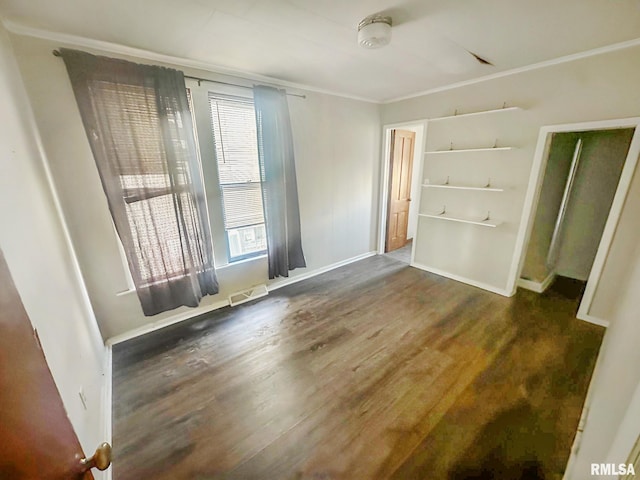 spare room with baseboards, visible vents, wood finished floors, and ornamental molding