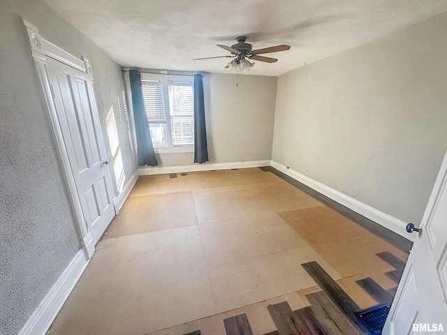 unfurnished room with ceiling fan and baseboards