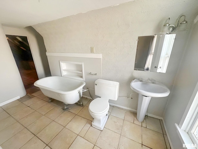 bathroom featuring toilet, a soaking tub, tile patterned flooring, and baseboards