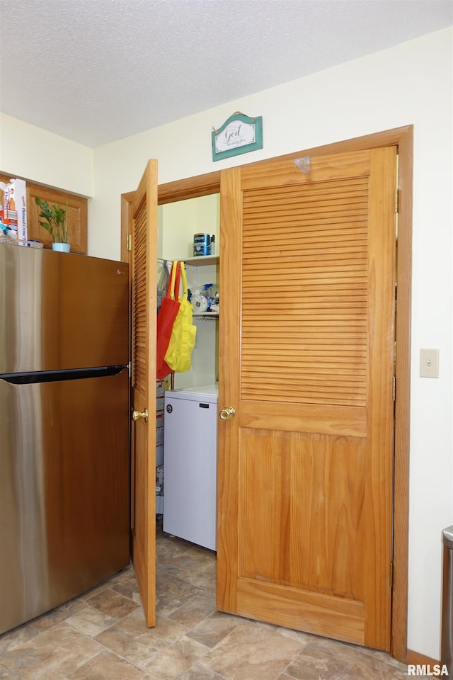 kitchen with fridge, stainless steel fridge, and a textured ceiling