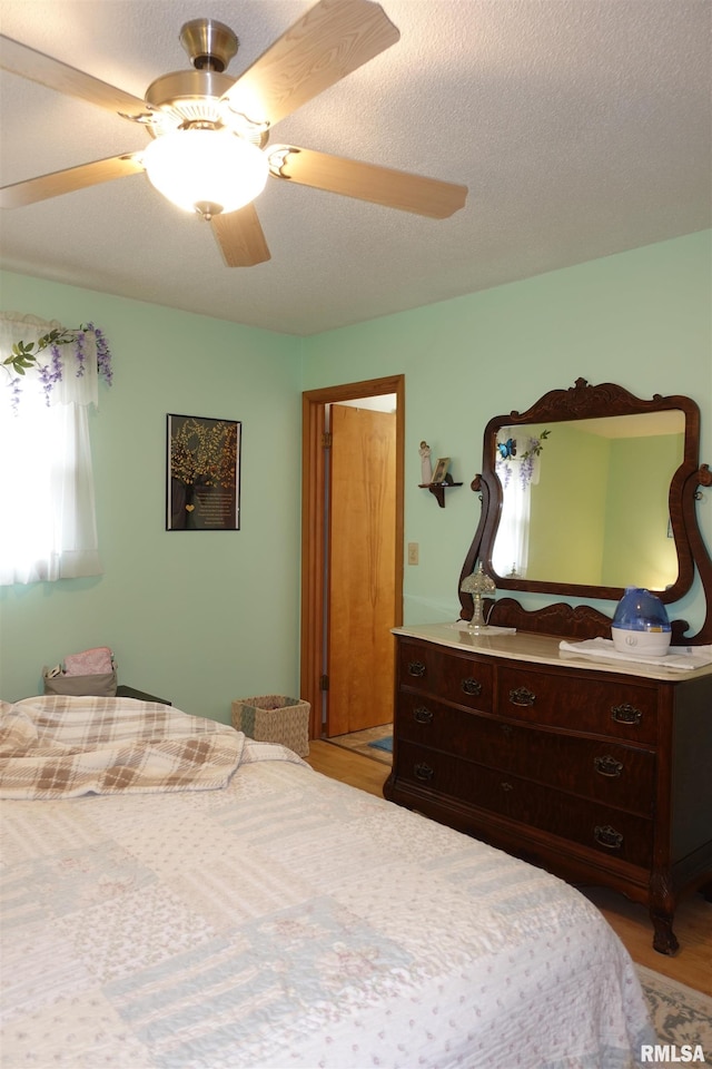 bedroom with light wood-type flooring, a textured ceiling, and ceiling fan