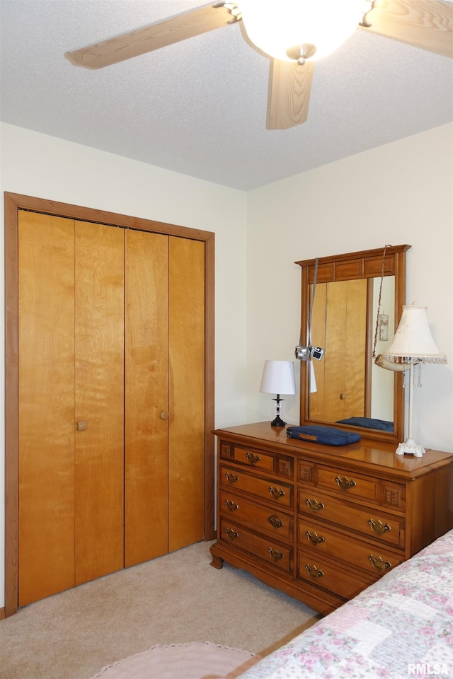 bedroom featuring light colored carpet, a textured ceiling, ceiling fan, and a closet