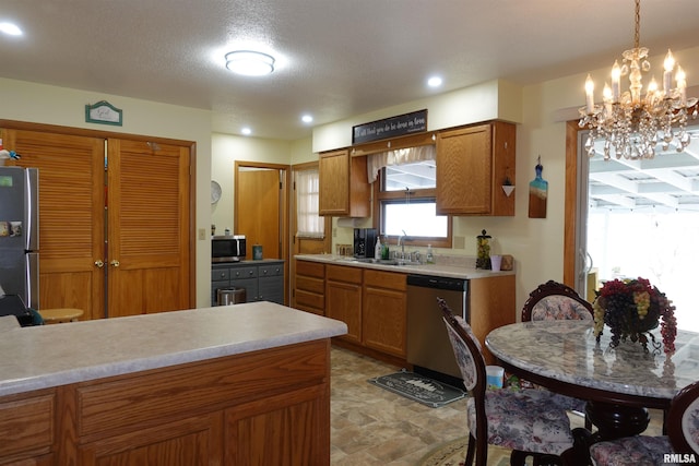 kitchen featuring pendant lighting, sink, stainless steel appliances, and a textured ceiling