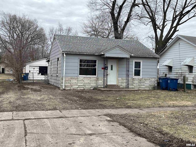 bungalow-style house featuring a garage and an outbuilding