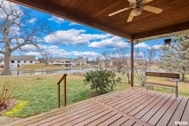 wooden terrace with a water view, ceiling fan, and a lawn