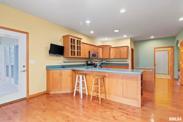 kitchen featuring appliances with stainless steel finishes, sink, light hardwood / wood-style floors, and kitchen peninsula