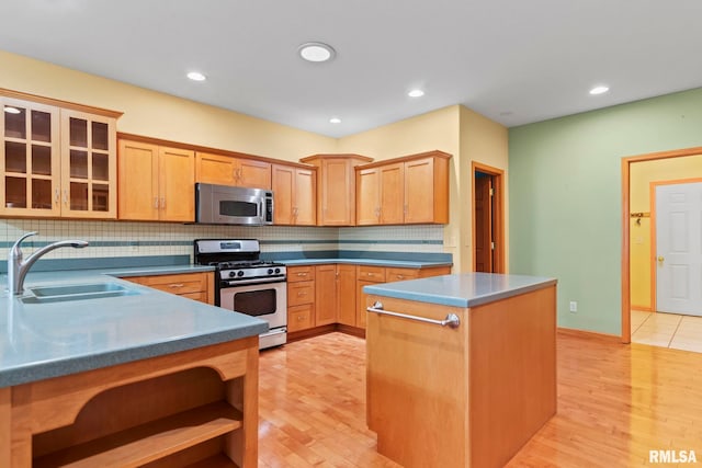 kitchen with light brown cabinetry, sink, light hardwood / wood-style flooring, stainless steel appliances, and decorative backsplash