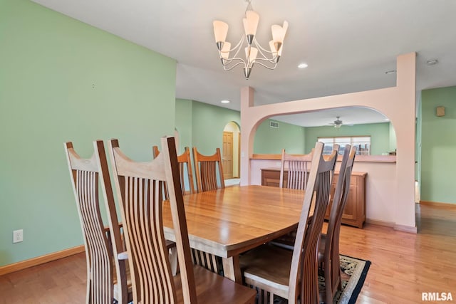 dining area with ceiling fan with notable chandelier and light hardwood / wood-style floors