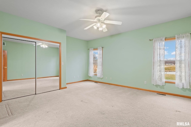 unfurnished bedroom with multiple windows, carpet flooring, ceiling fan, and a closet