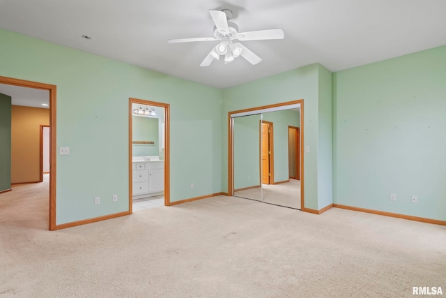 unfurnished bedroom featuring ensuite bathroom, light carpet, ceiling fan, and a closet