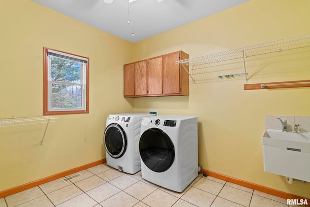 laundry area featuring cabinets, light tile patterned flooring, sink, and washer and clothes dryer