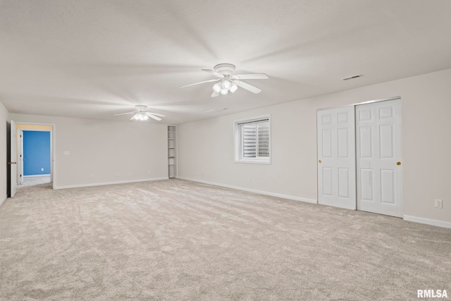 unfurnished room featuring light carpet, a textured ceiling, and ceiling fan