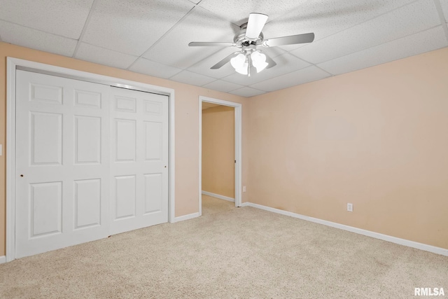 unfurnished bedroom with a paneled ceiling, a closet, ceiling fan, and carpet flooring