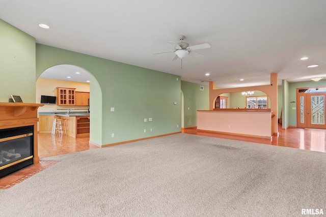 carpeted living room featuring ceiling fan with notable chandelier