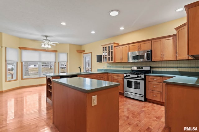 kitchen featuring tasteful backsplash, a center island, kitchen peninsula, and appliances with stainless steel finishes