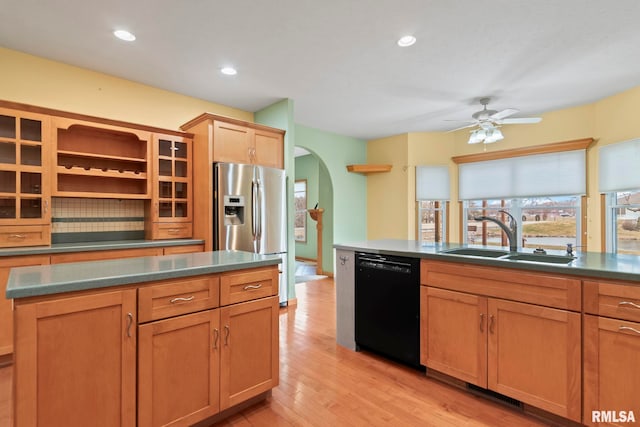 kitchen featuring sink, light hardwood / wood-style flooring, stainless steel fridge, black dishwasher, and backsplash