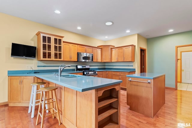 kitchen with sink, backsplash, a center island, kitchen peninsula, and stainless steel appliances