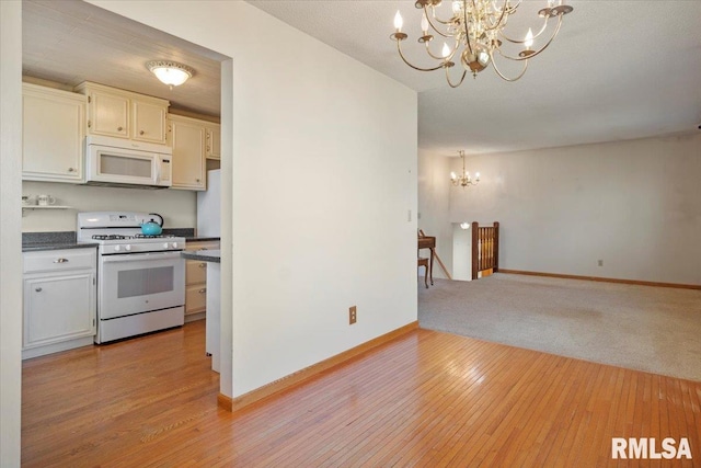 kitchen featuring pendant lighting, a chandelier, white appliances, and light hardwood / wood-style flooring