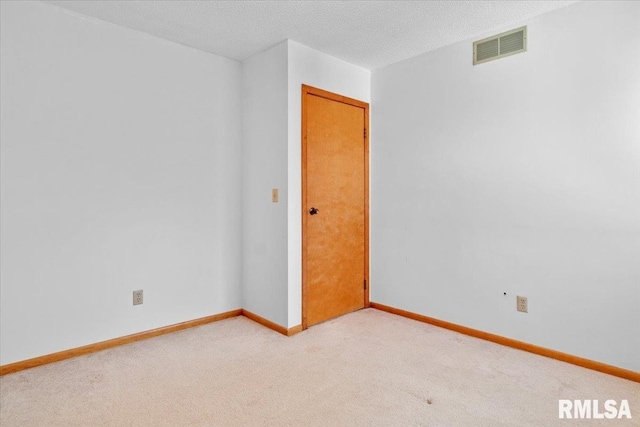 spare room featuring light carpet and a textured ceiling