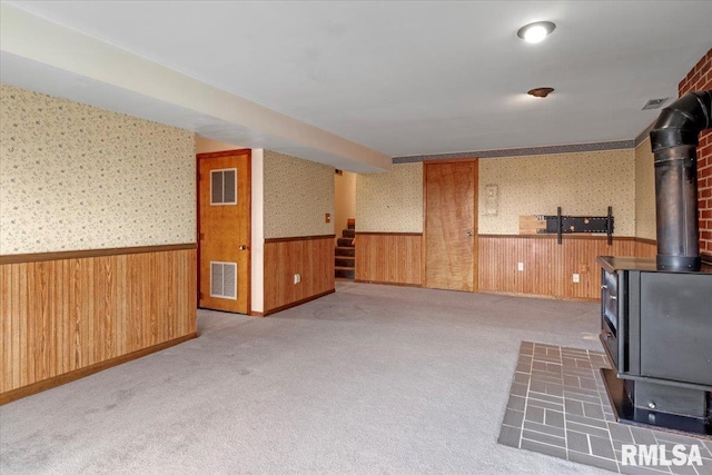 interior space with dark carpet, wooden walls, and a wood stove