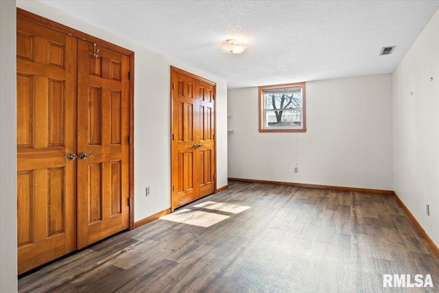 unfurnished bedroom featuring dark hardwood / wood-style floors, a textured ceiling, and a closet