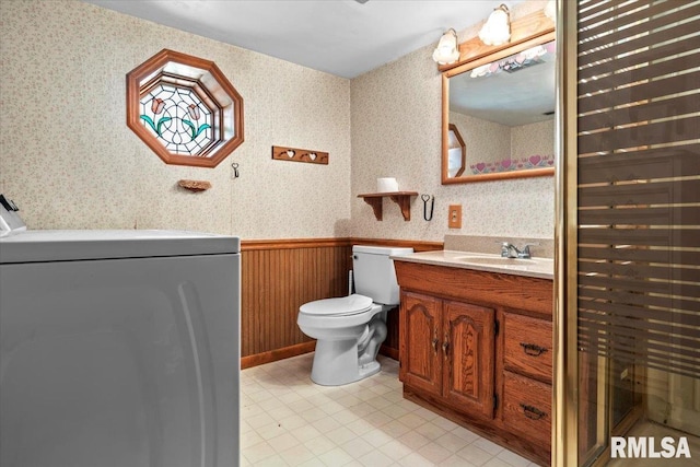 bathroom featuring vanity, washer / dryer, and toilet