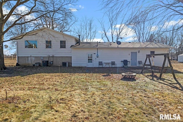 rear view of house featuring a yard, central AC, and a fire pit