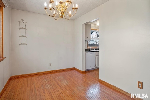 spare room featuring a chandelier and light hardwood / wood-style floors