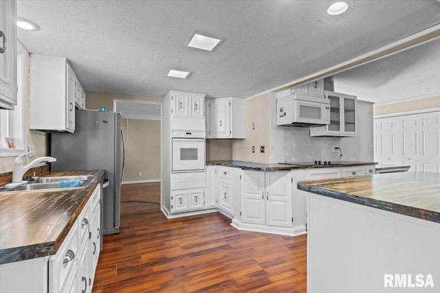 kitchen with white appliances, wooden counters, dark wood-style flooring, a sink, and white cabinetry