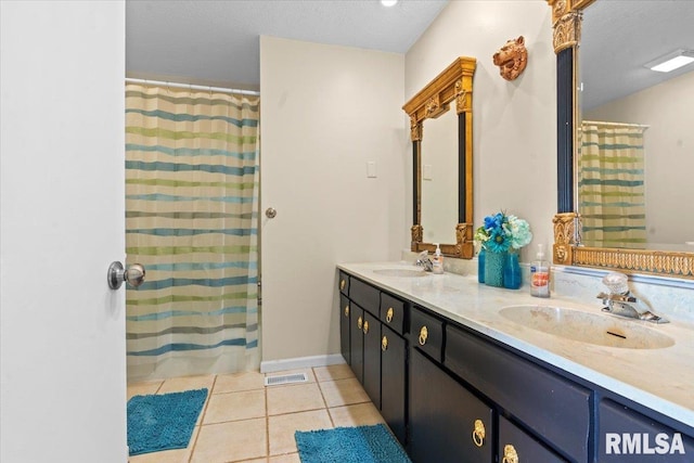 bathroom with tile patterned flooring, double vanity, a textured ceiling, and a sink