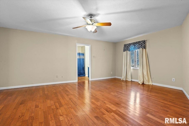 empty room featuring hardwood / wood-style floors, a textured ceiling, baseboards, and ceiling fan