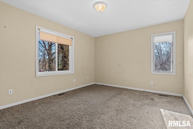 carpeted spare room featuring visible vents and baseboards