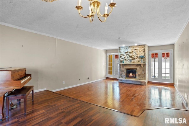 unfurnished living room featuring a fireplace, wood finished floors, french doors, and a textured ceiling