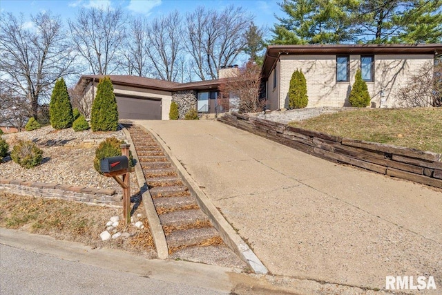 view of front of property featuring brick siding, a chimney, concrete driveway, and an attached garage