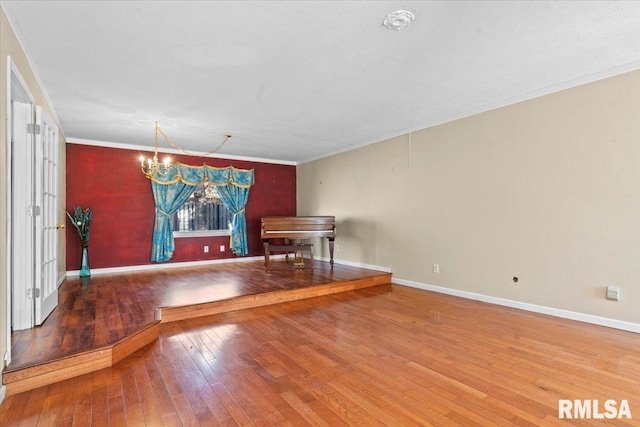 unfurnished dining area featuring an inviting chandelier, hardwood / wood-style flooring, crown molding, and baseboards