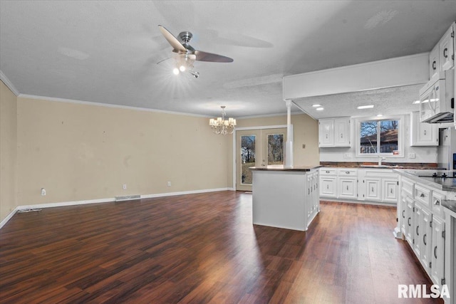 kitchen with dark wood finished floors, visible vents, white cabinets, and ornamental molding