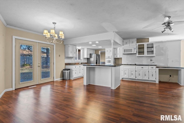 kitchen featuring dark countertops, dark wood finished floors, french doors, white appliances, and white cabinetry