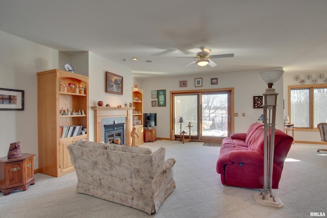 carpeted living room with ceiling fan and a fireplace