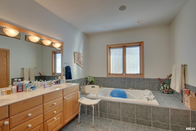 bathroom featuring tile patterned flooring, vanity, and tiled bath