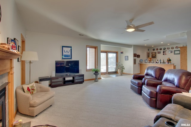 living room featuring light colored carpet, a tile fireplace, and ceiling fan