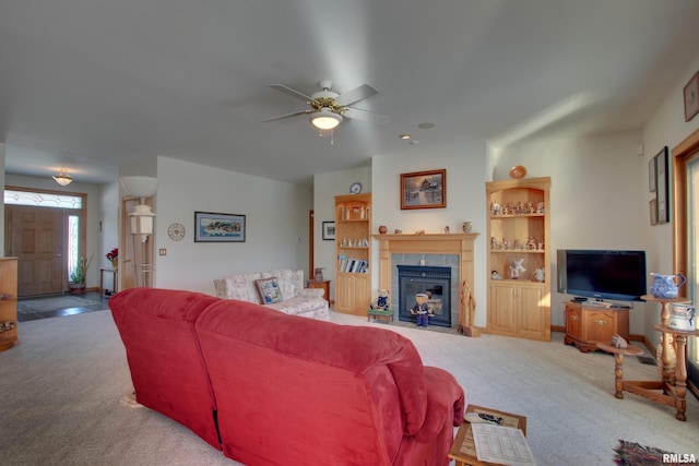 living room featuring a tile fireplace, carpet floors, and ceiling fan