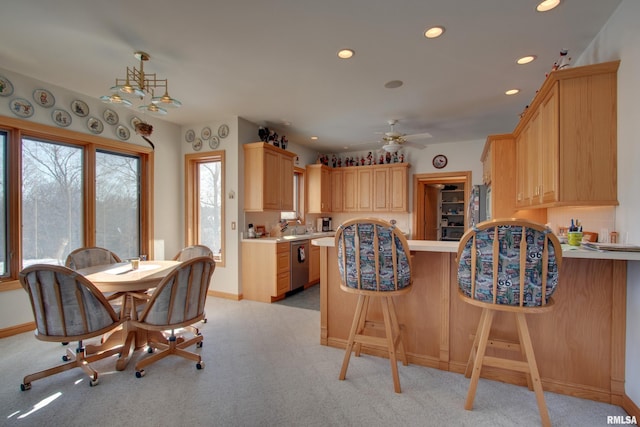 kitchen with pendant lighting, stainless steel appliances, light brown cabinetry, light colored carpet, and kitchen peninsula