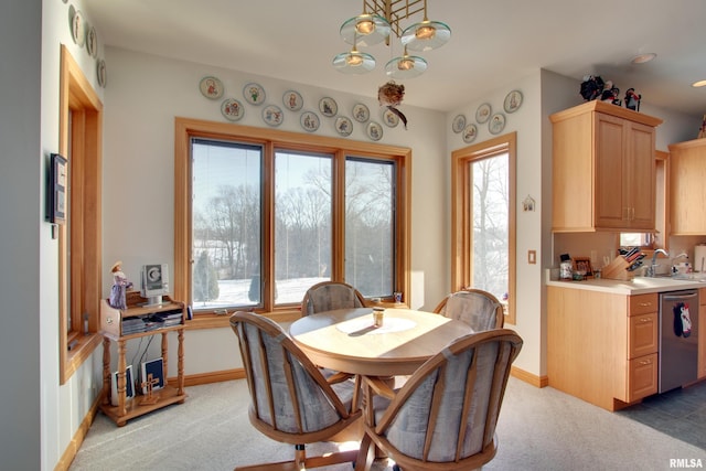 carpeted dining room featuring sink, a wealth of natural light, and an inviting chandelier