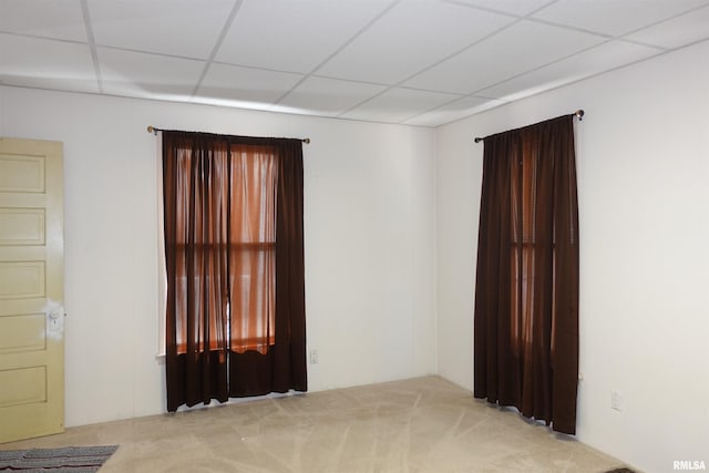 empty room with light colored carpet and a drop ceiling