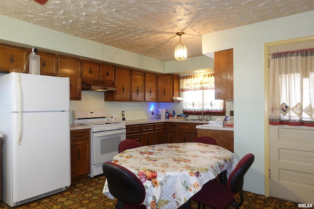 kitchen with pendant lighting, white appliances, sink, and a textured ceiling