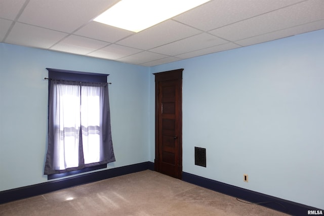 carpeted spare room featuring a drop ceiling