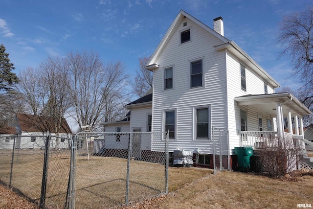 view of side of home featuring covered porch and a lawn