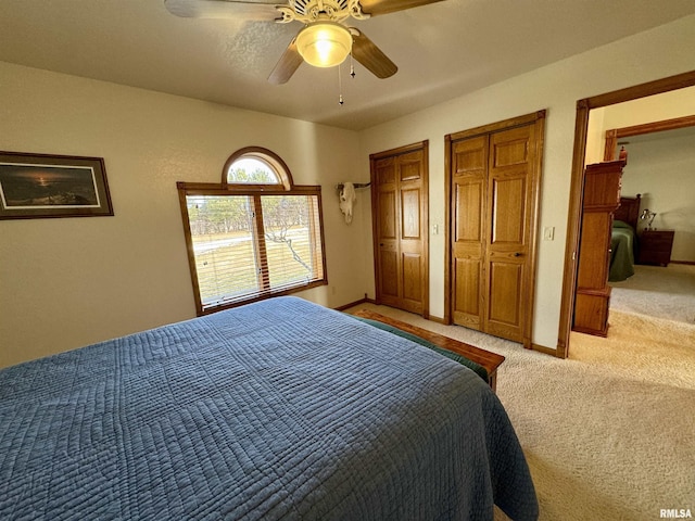 carpeted bedroom with multiple closets and ceiling fan